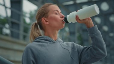 Sağlıklı kadın koşucu yorgun sporcu sporcu kadın spordan sonra susuzluğunu giderir spordan sonra şehir parkında filtrelenmiş soğuk su içer şişe vücut sıvısı konseptinin protein içeceğini tadar