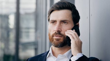 Cep telefonuyla konuşan ciddi bir adamın portresi. İş görüşmeleri. Başarılı iş adamı, profesyonel yönetici danışman.