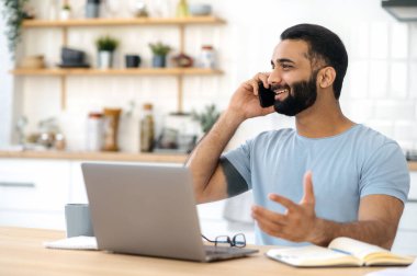 Meşgul, başarılı bir Hintli, bilişim uzmanı ya da serbest çalışan, çalışma masasında oturan, mesai saatlerinde cep telefonuyla konuşan, gülen, yüzünü çeviren. Cep telefonu iletişimi