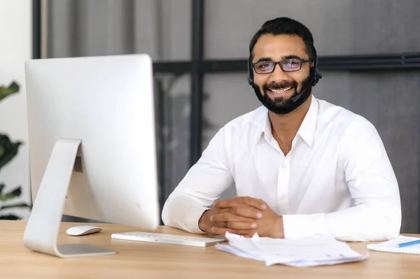 Portret van een knappe positieve intelligente Indiase man met bril en headset, expert, adviseur of mentor, kijkt direct naar de camera, glimlachend vriendelijk. Ondersteuningsconcept, hotline — Stockfoto