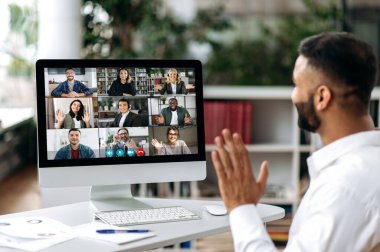 Video görüşmesi, online konferans. Bilgisayar ekranında, Hintli bir adamın omuz hizasında başarılı iş adamlarından oluşan çok uluslu bir grupla konuşuyor, sanal iş toplantısı, telekomünikasyon konsepti