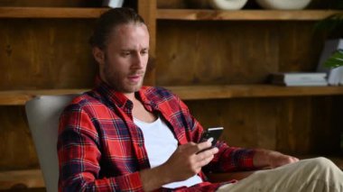 Tatmin olmuş çekici adam bir koltukta oturuyor, akıllı telefon kullanıyor, kanalda vakit geçiriyor. Gülümseyen adam iyi bir haber ya da mesaj almış, internette geziniyor, arkadaşlarıyla ya da ailesiyle sohbet ediyor.