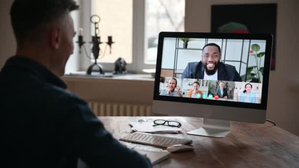 Video call concept. Side view at caucasian confident man, manager or freelancer, and at computer screen with business partners gathered in a group online conference to discuss work issues and strategy — Stock Video