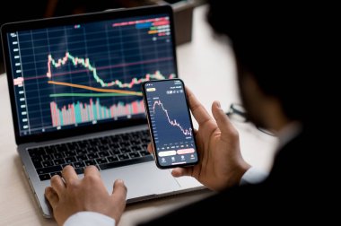 Dizüstü bilgisayara yakın çekim ve diyagramlı akıllı telefon ekranı. Kripto, borsa simsarı akıllı telefon ve dizüstü bilgisayar kullanarak kripto para piyasası analizi, kripto para alımı veya satışı yapıyor.