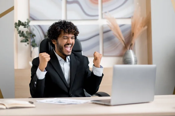 행복하게 흥분 한 인도 남자, 정장을 입고, 사업을 하는 사람, 사무실에 책상에 앉아, 좋은 소식을 가지고 승리, 성공, 좋은 거래, 큰 이익, 행운의 사람 — 스톡 사진