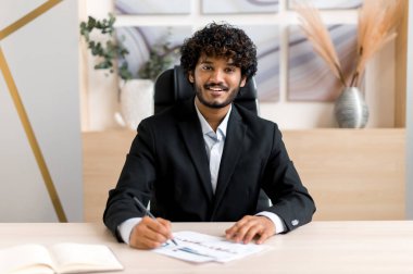 Vesikalık fotoğraf başarılı Hintli iş adamı, finansal danışman, iş arkadaşı ya da müşteriyle video bağlantısı yoluyla konuşuyor, sanal görüşme yapıyor, kameraya bakıyor, notlar alıyor, gülümsüyor.