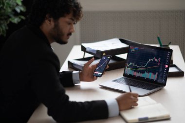 Akıllı odaklı Hintli borsacı, akıllı telefon ve dizüstü bilgisayar kullanan borsacı kripto para piyasasını analiz etmek, satın almak veya satmak, kripto sikke planlama stratejisi