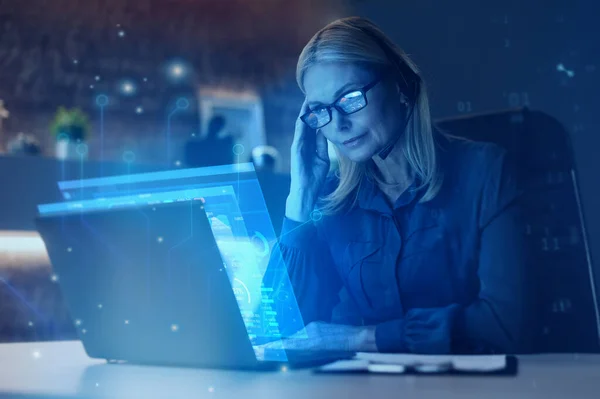 Focused mature blonde woman, executive, ceo, financial expert, stock broker, using laptop, sitting at workplace, working, analyzing financial data, doing research, planning strategy. Future technology — 图库照片