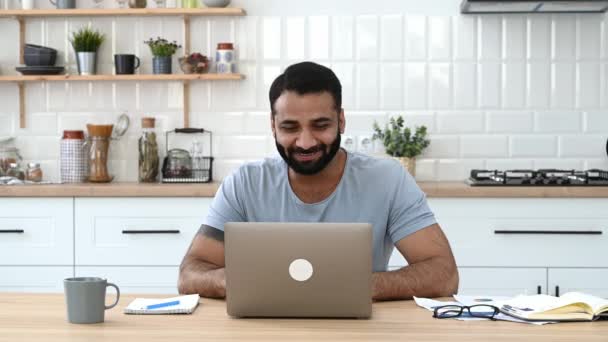 Vidéo conférence, communication à distance. Homme indien positif, pigiste, designer ou manager, travailler de la maison, utiliser un ordinateur portable pour la communication par appel vidéo, parler à un collègue ou un ami, sourit — Video