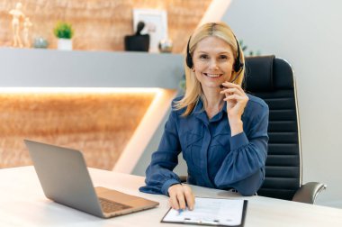 Hoş, kendine güvenen, orta yaşlı, orta yaşlı, kulaklı, finans uzmanı, çağrı merkezi çalışanı ya da iş danışmanı, resmi şık bir takım elbise giymiş, doğrudan kameraya bakıyor, güler yüzlü, arkadaş canlısı.