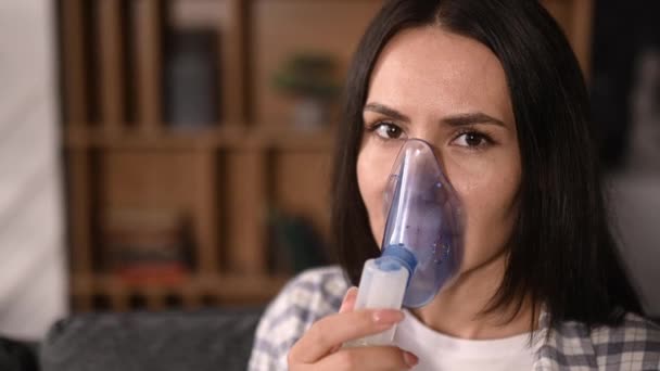 Mujer caucásica enferma con un inhalador. Mujer triste poco saludable haciendo inhalación usando nebulizador e inhalador para el tratamiento de la tos y la gripe, sentado en casa en la sala de estar. Concepto de resfriado y gripe — Vídeo de stock