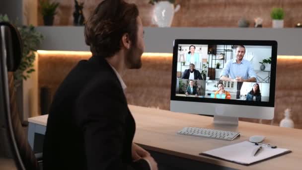 Video call, online conference. Over shoulder view of business man, on computer screen with multinational group of successful business people, virtual business meeting, telecommunication concept — 图库视频影像