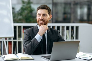 Attractive confident influential caucasian bearded businessperson, ceo of company, top manager, in formal suit, sitting in modern office, looking to the side, thinking strategy, smiling friendly