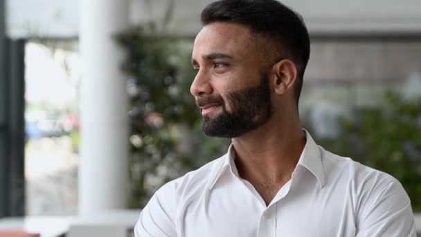 Close-up video portrait of a successful intelligent influential Indian businessman, corporate top manager or IT specialist, in white shirt, looking at the camera, stand in modern office, smiles — Vídeo de Stock