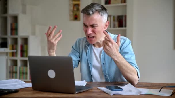 Angry annoyed caucasian adult man, ceo, top manager, emotionally yells at a laptop during video conference with colleagues, got bad news, gesturing with hands, very irritated and frustrated — Stockvideo