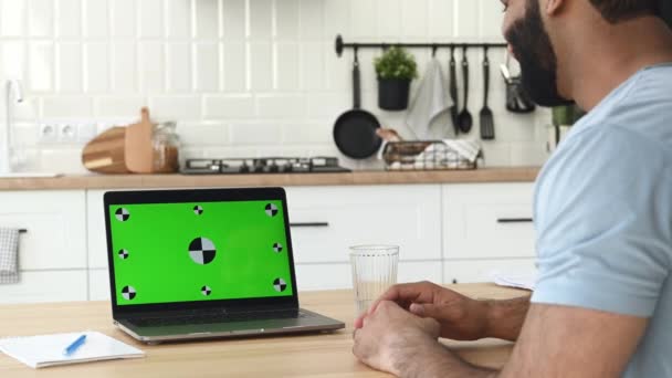 Green screen laptop for your insertion. Indian man, freelancer, working remotely from home, using laptop to communicate with colleagues via video conference, discuss goals and strategy — Vídeo de Stock