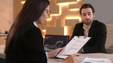 A smart caucasian man in formal clothes, comes to get a job in a company as a stock trader, broker, is interviewed with female boss, shows resume. Hiring manager looking at resume, conducts interview