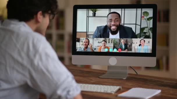 Jovem caucasiano bem sucedido conversando em videoconferência com colegas de diferentes nacionalidades, discutindo o projeto e a estratégia. Reunião de negócios online, brainstorm de funcionários — Vídeo de Stock