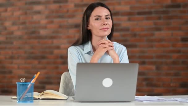 Retrato adorável confiante jovem adulto bem sucedido trabalhador de escritório caucasiano, senhora de negócios, gerente corporativo, na camisa formal, sentar-se no escritório moderno com laptop, olhando para o lado e do que na câmera, sorriso — Vídeo de Stock