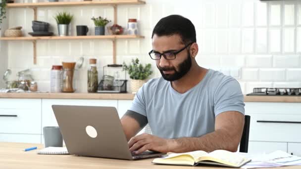 Upset tired Indian man, freelancer or IT specialist, works from home, in a kitchen, finished work, closed the laptop, massaging eyes, need a rest, have a stressful situation, have headache, migraine — Vídeo de Stock