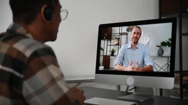 Video call, online conference. Over shoulder view of mixed race Latino man, on computer screen with caucasian successful business partner, virtual business meeting, talking by internet via video call