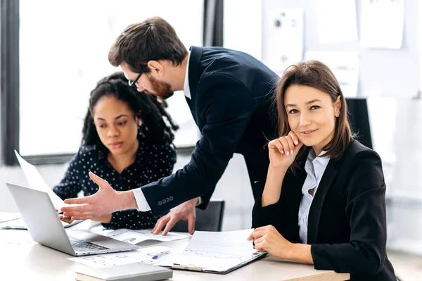 Una lluvia de ideas corporativa. Equipo de negocios multirracial exitoso creativo, trabajando en un proyecto de negocio, puesta en marcha, en una oficina moderna. Mujer inteligente de negocios mirando a la cámara, sonriendo amigable — Foto de Stock