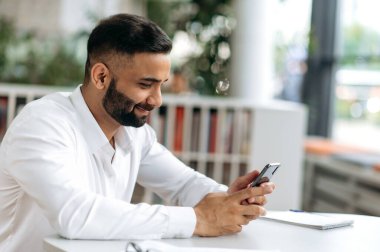 Mesajlaşmaya çalışıyorum. Hoş, başarılı bir Hintli adam, bir tüccar, üst düzey bir yönetici, masasında oturur, mesai saatlerinde cep telefonuyla iş yazışmaları yönetir, dostça gülümser.