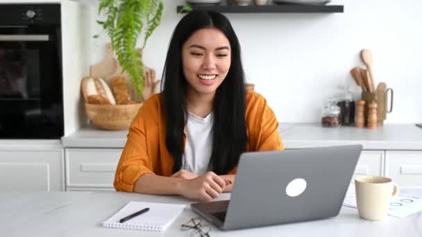 Mujer asiática encantadora positiva, estudiante china, freelancer o diseñadora, trabajando o estudiando remotamente, hablando en videoconferencia usando laptop, discutiendo proyecto, escuchando webinar, sonriendo — Vídeos de Stock