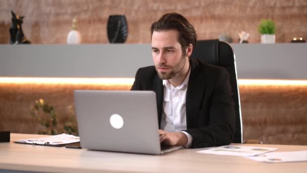 Joyful feliz bem sucedido líder de negócios caucasiano, gerente de topo, comerciante de ações, de terno, sentado no escritório moderno, usando laptop, alegrando-se com sucesso ou bom lucro, gesticulando com as mãos, sorrindo — Vídeo de Stock