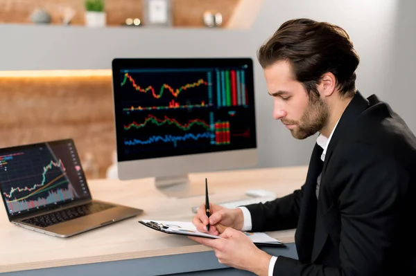 Stock market concept. Focused smart successful caucasian businessman, trader investor, broker, sits at a desk in a modern office, in formal suit, analyze trading charts, predicts profit — Stock Photo, Image