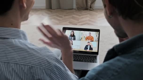 Zwei Typen, die sich lieben, schwules Paar, zu Hause im Wohnzimmer auf dem Sofa sitzen, per Videokonferenz mit Freunden kommunizieren, Nachrichten erzählen, einen Termin vereinbaren — Stockvideo