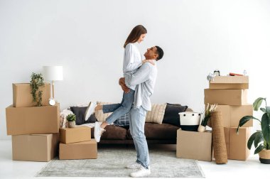 Sevgi dolu genç bir çift yeni evlerinde seviniyor. Adam sevgili karısını kollarında tutuyor, oturma odasında, yeni bir daireye taşınıyorlar, karton kutuların yanına. Emlak yatırımı