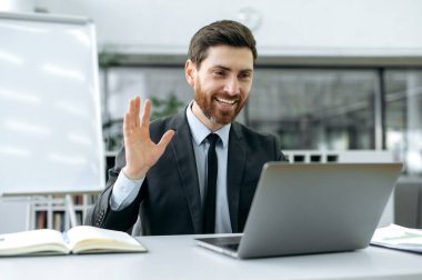 Uzaktan video bağlantısı. Modern ofiste oturan başarılı beyaz iş adamı, bilgisayar kullanıyor, online video konferansı yapıyor, iş arkadaşlarıyla iş stratejisi hakkında beyin fırtınası yapıyor.