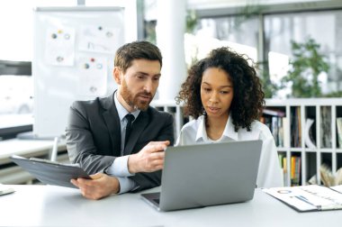 Başarılı iş arkadaşları, ofis çalışanları, finans danışmanları, ekonomistler, bir dizüstü bilgisayarın önünde, modern bir ofiste, çalışma stratejisi geliştirmek, verileri analiz etmek, iş kavramını tartışmak.
