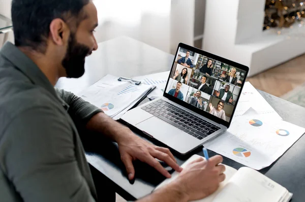 Üzleti eligazítás. Indiai srác nézi laptop képernyőn, beszél videohívás a multinacionális üzleti csoport, konferenciát tart, virtuális találkozó, ötletelés kollégáival az interneten, jegyzetel — Stock Fotó