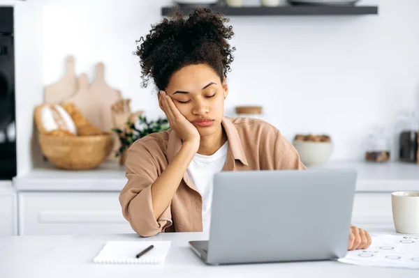 Exhausted african american girl with closed eyes, freelancer or student, working remotely from home, tired of boring online work, suffering from chronic fatigue, overwork, falls asleep at the desk — Stock Photo, Image