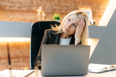 Çok çalışan, yorgun, üzgün, Kafkasyalı, olgun iş kadını, kadın üst yönetici, ofis çalışanı işten yorgun, stresli, dinlenmeye ihtiyacı var, üzgün görünüyor.