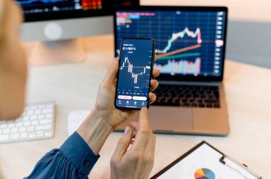 Yakın plan dizüstü bilgisayar ve cep telefonu ekranı. Şifreli para birimi analizi, kripto para birimi alımı veya satışı için cep telefonu ve dizüstü bilgisayar kullanan kadın bir kripto simsarı.
