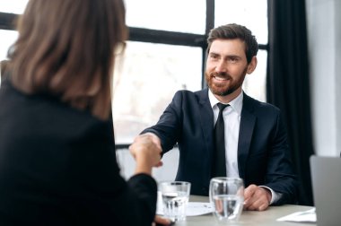 El sıkışmak, anlaşma yapmak, anlaşmalar yapmak. Beyaz tenli, etkileyici, başarılı, başarılı iş adamı, geliştirme patronu, CEO şirketi, modern ofisteki kadın meslektaşlarıyla tokalaşıyor, birbirlerine gülümsüyorlar.