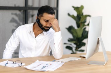 Baş ağrısı ve migren. Yorgun Hintli ya da Arap adam, borsacı, finans danışmanı, ofis çalışanı, çalışmaktan yorgun, stresli, dinlenmeye ihtiyacı olan, elleriyle gözlerini kapatan