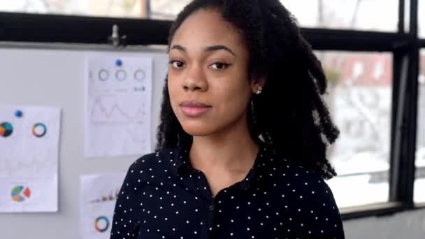 Close-up de uma mulher de negócios afro-americana muito elegante positivo, gerente financeiro ou mentor, corretor, comerciante, ficar no escritório, olhando para a câmera, sorrindo amigável — Vídeo de Stock