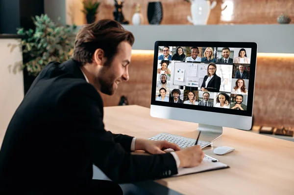 Communication by video conference, financial briefing. Intelligent business man, sit in office, conducts a brainstorm with multiracial business team, discussing financial strategy and analyzing risks — Stok Foto