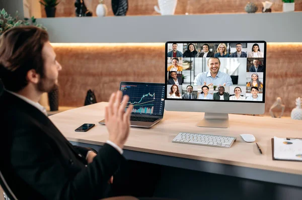 Videokonferencia üzleti partnerekkel. Sikeres kaukázusi férfi tőzsdeügynök ül a modern irodájában, videóhívást folytat kollégáival, kidolgozza a titkosítási stratégiát, megvitatja a kockázatokat. — Stock Fotó
