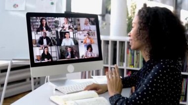 Video konferansı. Başarılı Afrikalı Amerikalı kadın, şirket çalışanı, bir bilgisayarın önünde çalışma masasında oturuyor, online beyin fırtınası yapıyor, çok ırklı insanlarla iş konuşmaları yapıyor.