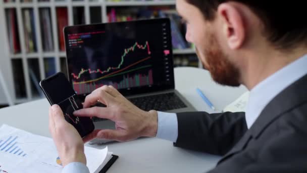 Close-up of a laptop and cellphone screen with stock diagrams. Crypto trader investor broker using cellphone and laptop for cryptocurrency financial market analysis, buying or selling cryptocurrency — Wideo stockowe