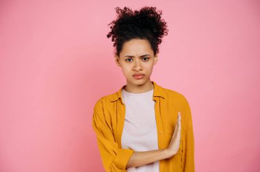 Üzücü kıvırcık saçlı Afro-Amerikan kızı, hayır diyor, avuç içi dolu, tatminsizliğini ifade eden, pembe renkli arka planda duran, kameraya bakan,