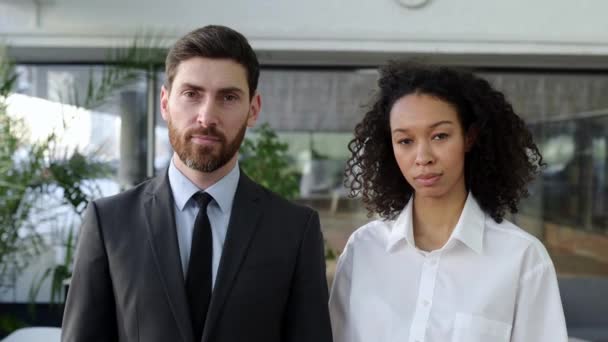 Influential successful coworkers of different nationalities, caucasian man and african american woman, in formal clothes, are standing with arms crossed in modern office, looking at camera and smiling — Vídeo de Stock