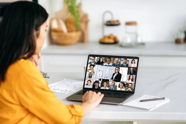 Online tanulás, szakmai fejlődés. Ázsiai lány, otthon ül, videokonferencia segítségével webináriumot hallgat, a képernyőn egy csapat multiracionális ember összegyűlt egy ötletbörzére vagy előadásra. — Stock Fotó