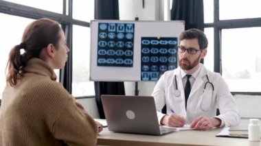 Beyaz önlük giyen, sağlıksız bir hastayla konuşan, tavsiye veren, tedavi öneren, ilaç yazan profesyonel bir terapist. Kafkas erkek doktor bir hastanede kadın hastaya danışmanlık yapıyor.
