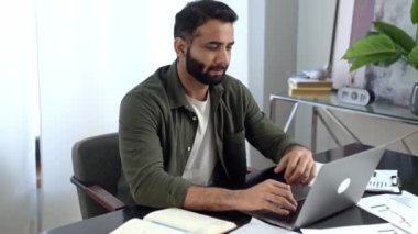 Düşünceli Hintli ya da Arap kıyafetleri içinde, serbest çalışan, tasarımcı, borsacı, modern ofiste oturan, dizüstü bilgisayar kullanan, başka yöne bakan, yeni bir proje düşünen, çevrimiçi çalışmalardan bıkmış